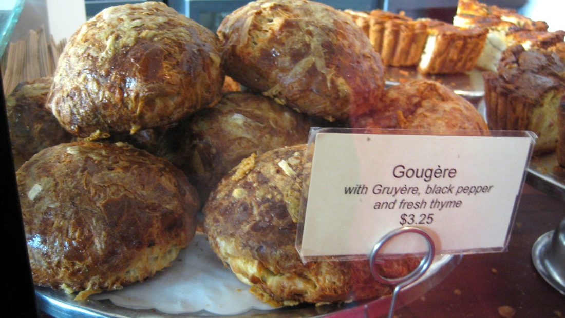 A morning rack of finished artisan loaves and a full pastry case behind the counter of my coffee shop and bakery