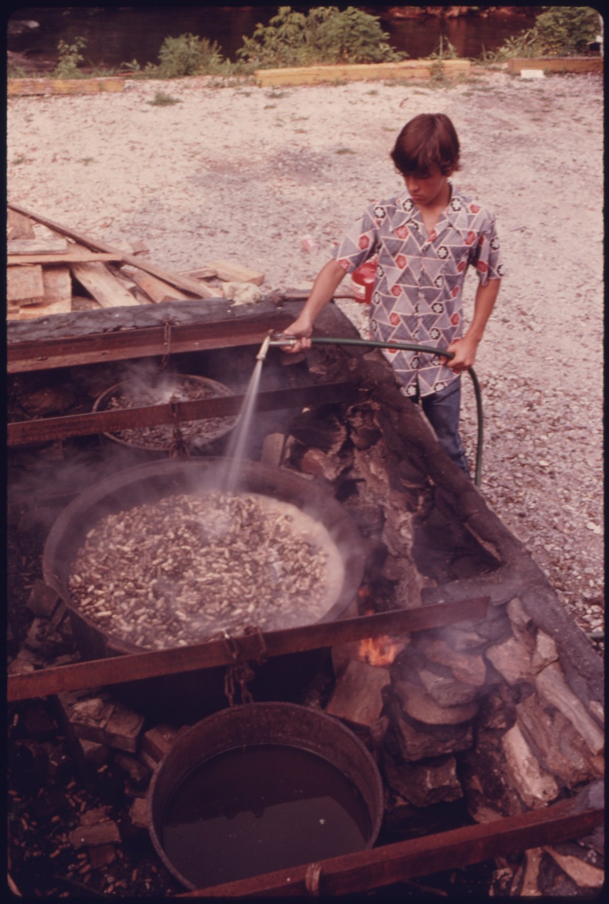 A youngster sprays water on boiling peanuts in Helen, Georgia — photographed for the US National Archives' DOCUMERICA project in the 1970s, and still exactly how a stand works