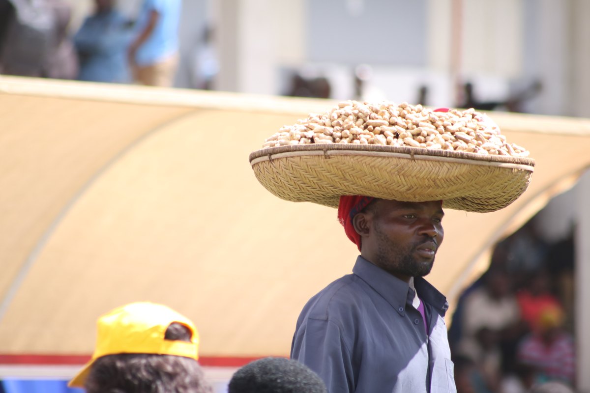 A street vendor selling groundnuts from a head tray