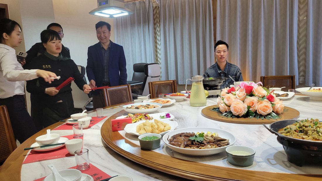 The round table, mid-meal — whole fish, prawns, a clay pot, greens and several stir-fries, all in the middle