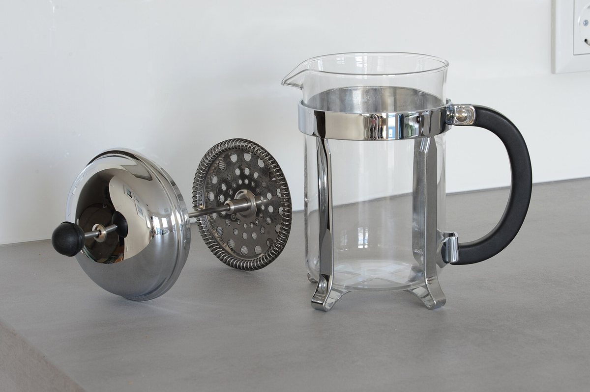 A French press with the plunger lifted out — that perforated metal disc and its coil spring are the device's entire personality