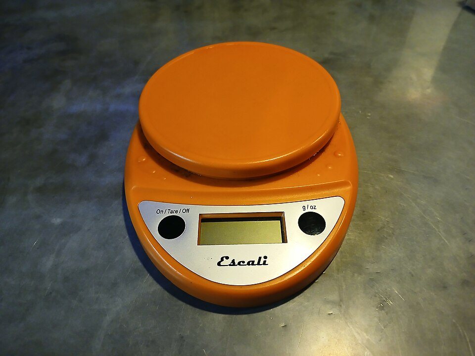 An orange digital kitchen scale with a round platform and a small display