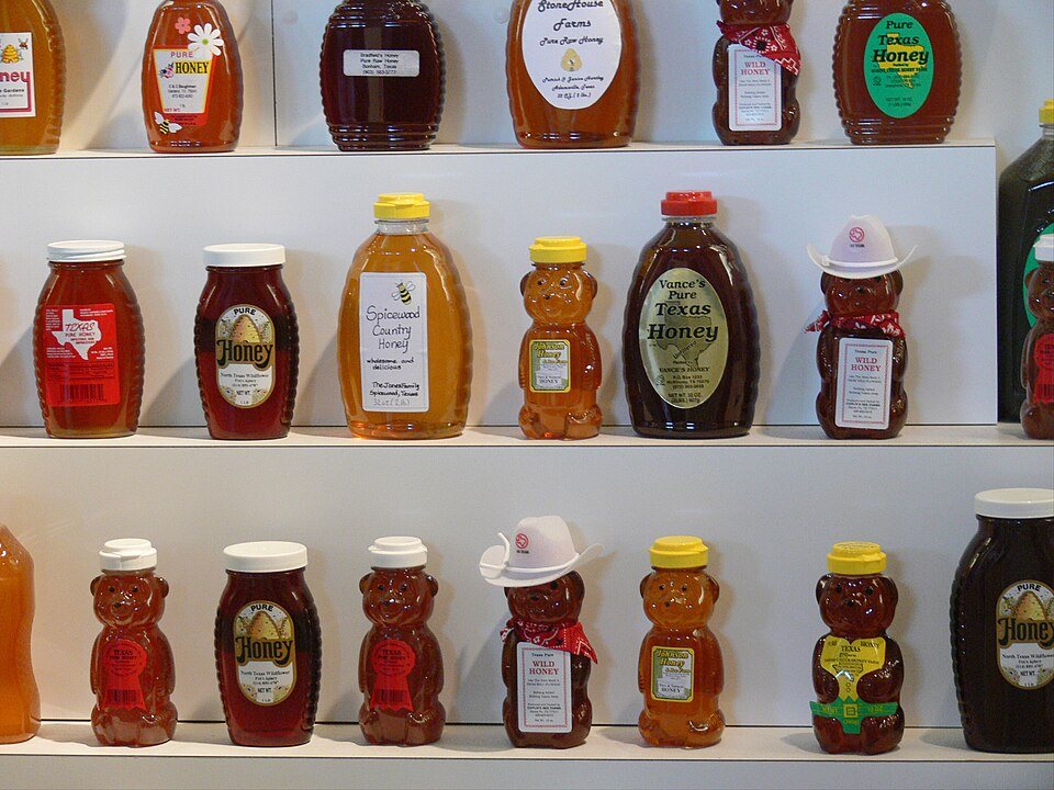 Shelves of honey in jars and bear-shaped bottles, ranging from pale gold to nearly black