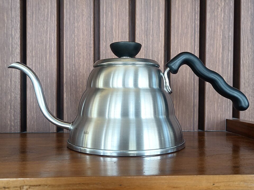 A stainless stovetop gooseneck kettle with a black handle and a long thin spout