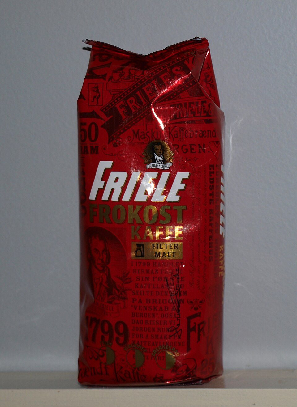 A red foil bag of Norwegian ground filter coffee standing on a shelf, the foil creased and tight around the contents