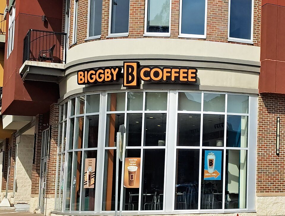 The corner storefront of a Biggby Coffee shop under an orange and black sign