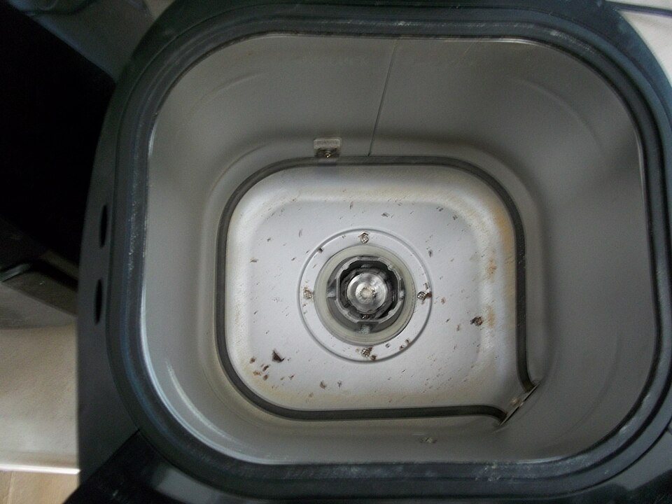 Looking down into an empty bread machine with the pan removed, the drive shaft for the kneading paddle at the centre