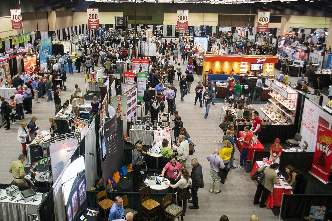 A crowded trade-show floor seen from above, aisles of exhibitor booths