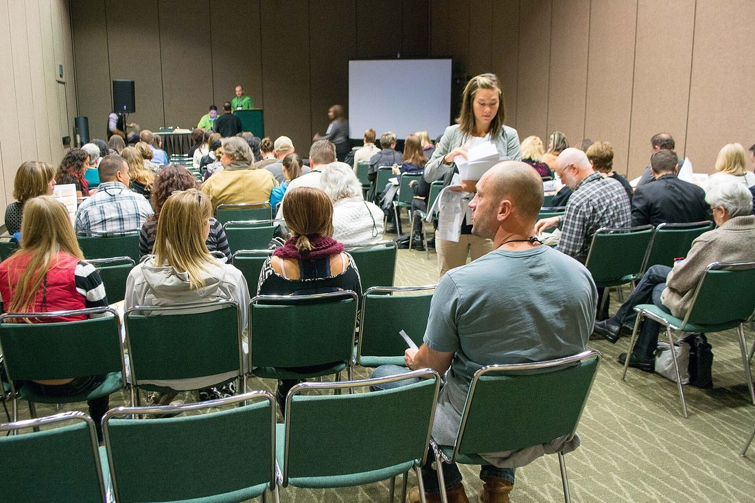 An audience seated in rows in a conference room listening to a speaker