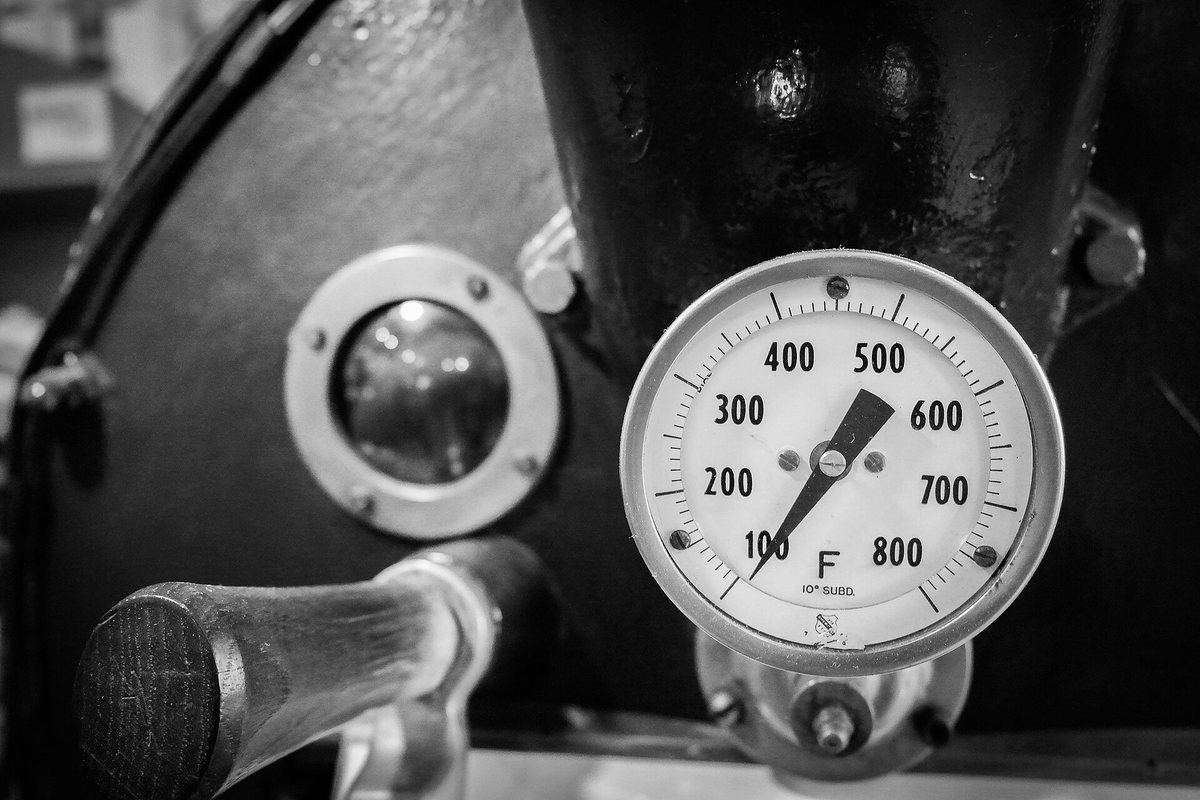 The drum's face: a sight glass to look through, a trier to pull samples with, and a thermometer reading somewhere between 400 and 800°F. Three instruments, and the roaster's nose