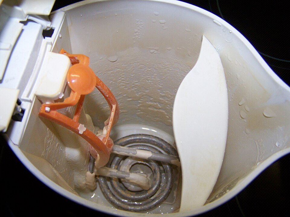 Looking into a white plastic electric kettle: the coiled element at the bottom is coated in chalky scale