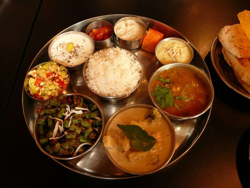A thali with several small bowls — dal, a vegetable sabzi, a meat curry, yoghurt and rice — the way the food is actually eaten
