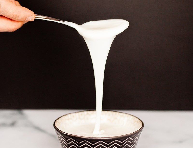 Viili pouring off a spoon in one long unbroken strand. That ropiness is the point of it, not a fault
