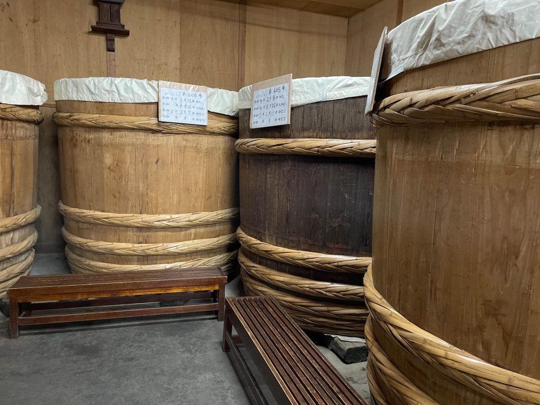Miso aging in big rope-bound wooden barrels, hand-labelled with their dates