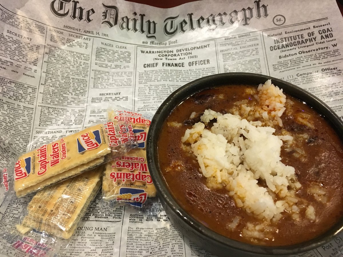 A bowl of gumbo set down on a newspaper