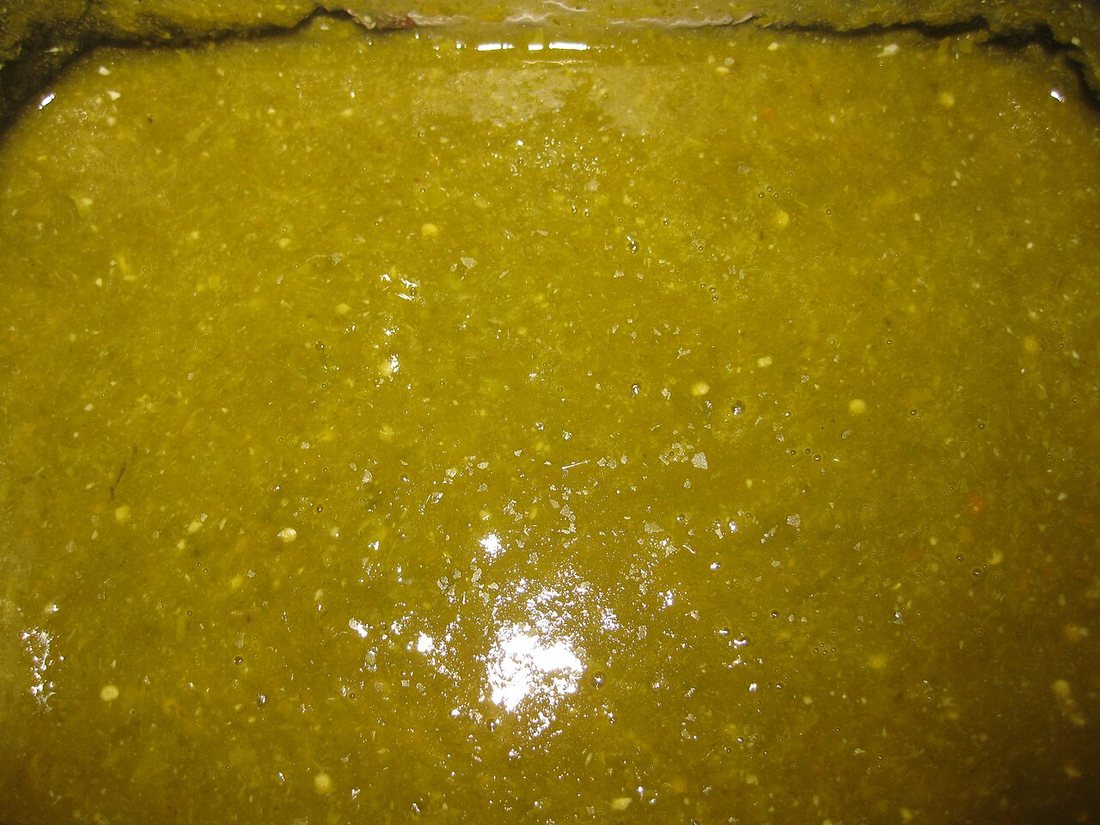 A tray of blended green jalapeño hot sauce, seeds and flecks of pepper visible