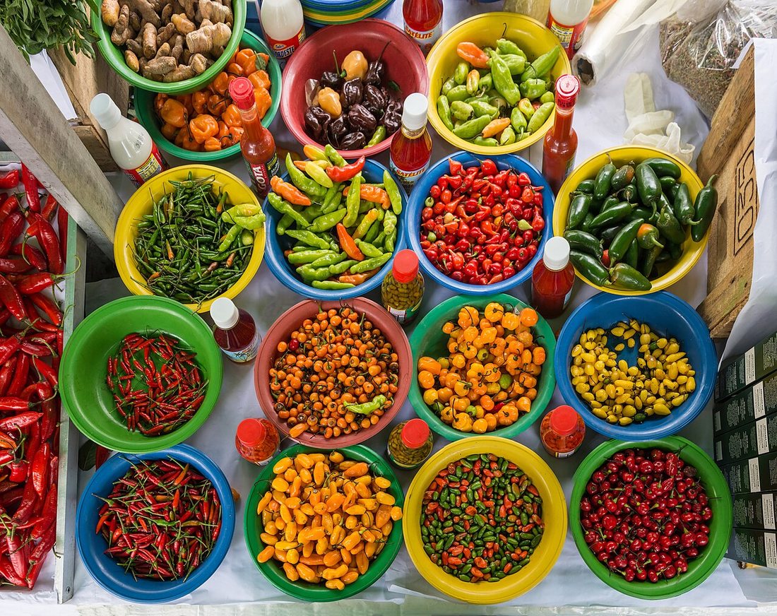 Bowls of red, yellow, orange and green chiles of many shapes at a market stall