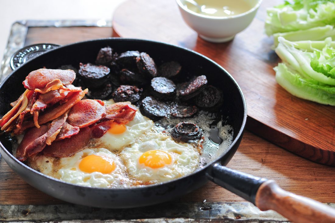 A pan of fried breakfast — rashers, eggs and black pudding cooking together