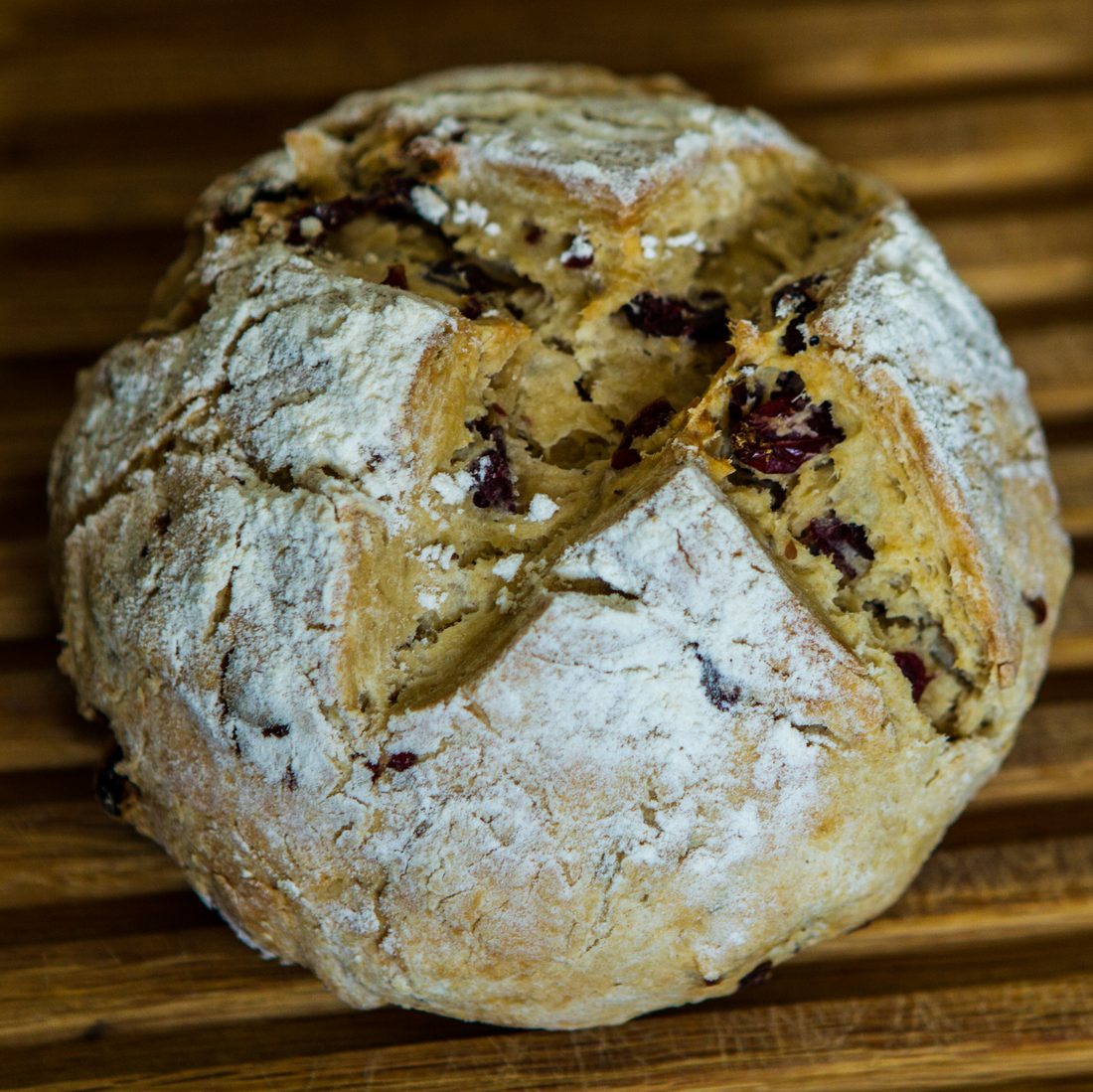 A round loaf of soda bread with a deep cross cut across the top