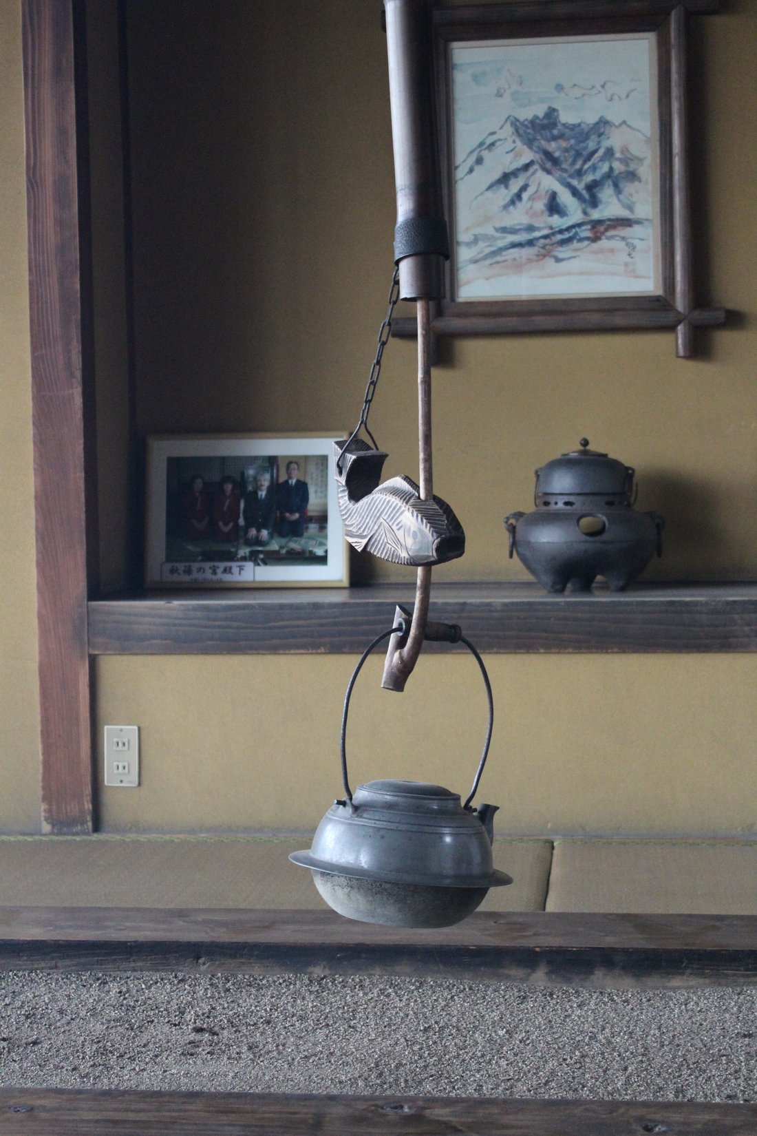An iron kettle hanging from a jizai-kagi. The hearth itself is out of frame here, but the hook is the point — it is what makes an open fire controllable