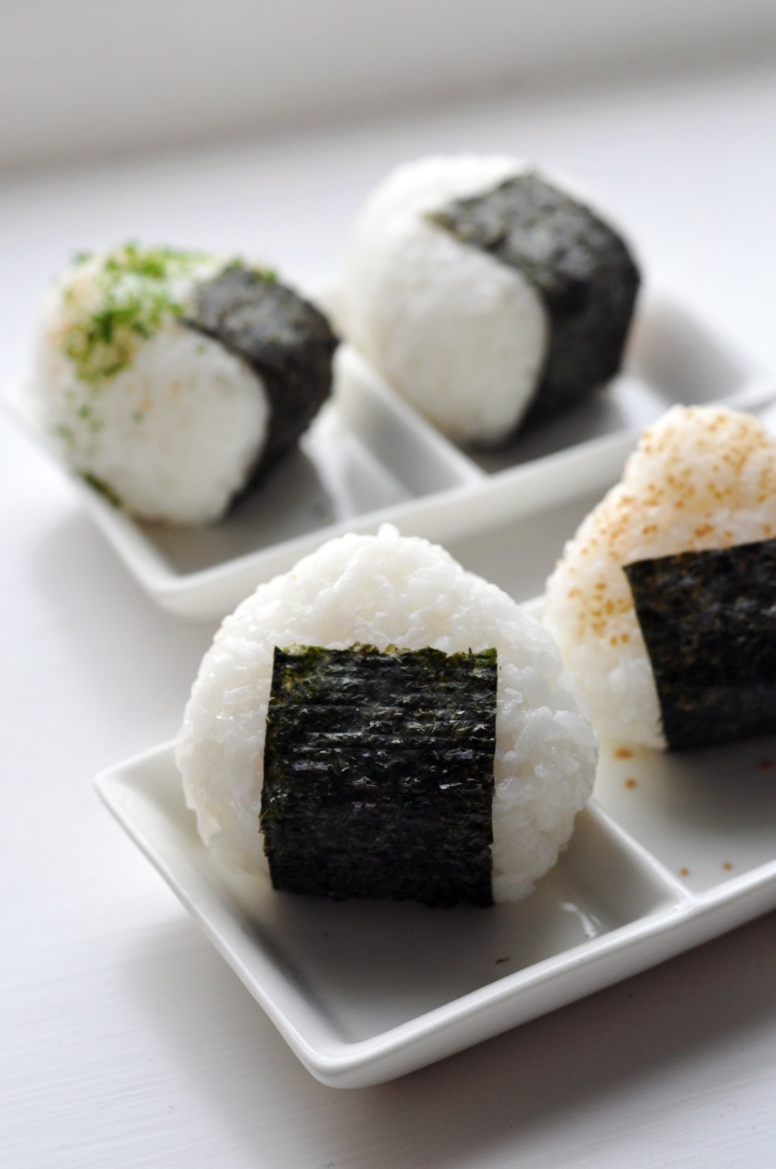 Onigiri, with the nori wrapped as a band around the middle. That band is a handle, and holding it is the whole reason it is there