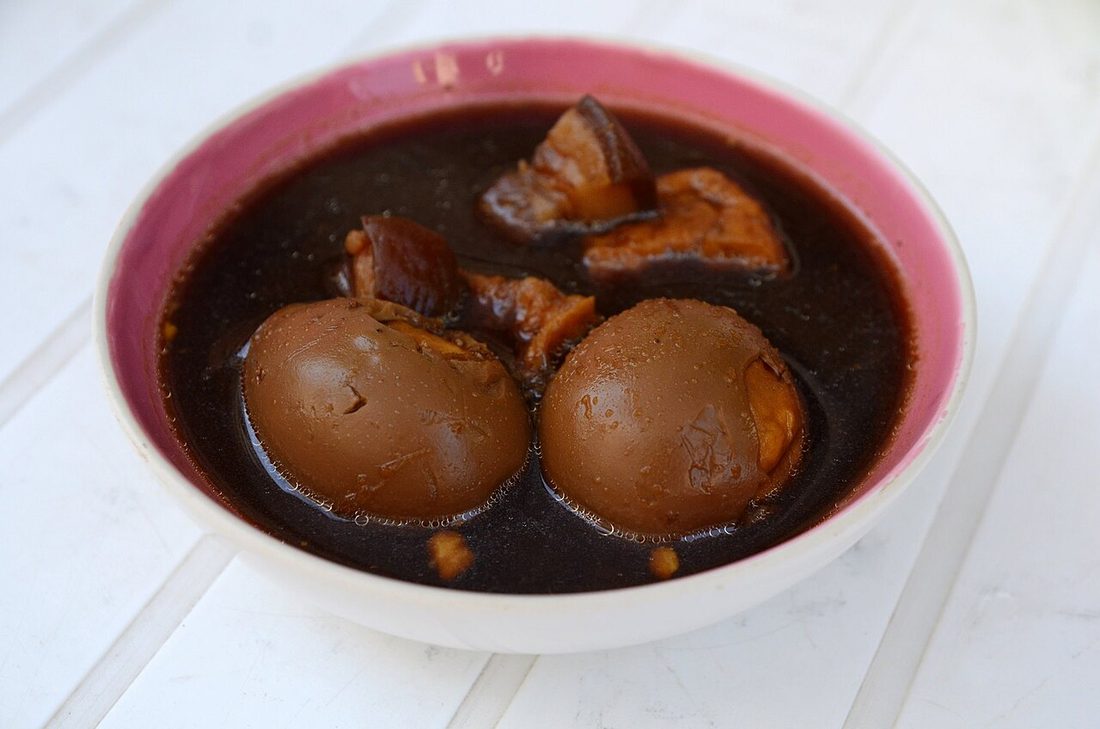 Whole peeled eggs braised dark in a soy stock alongside pieces of pork
