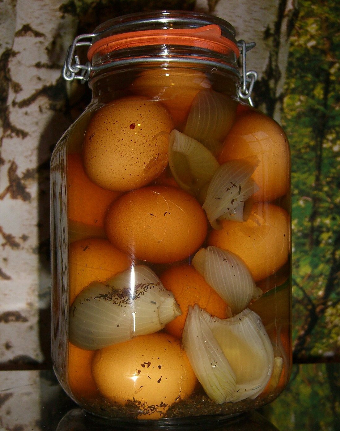 A glass jar of whole eggs and onions in spiced brine