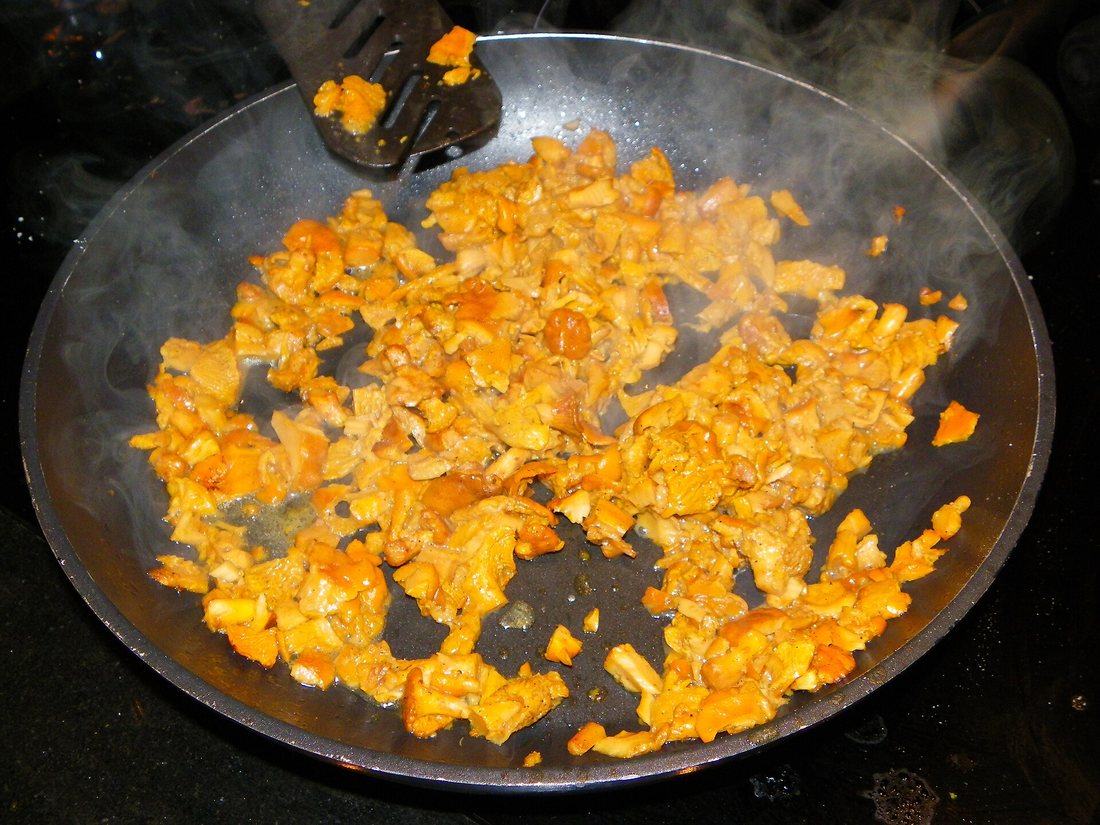 Chopped golden chanterelles cooking in a dark skillet