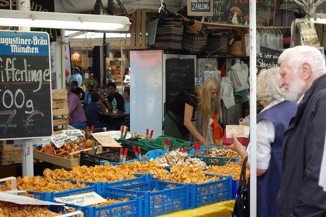 A market stall at Munich's Viktualienmarkt heaped with crates of chanterelles, with shoppers