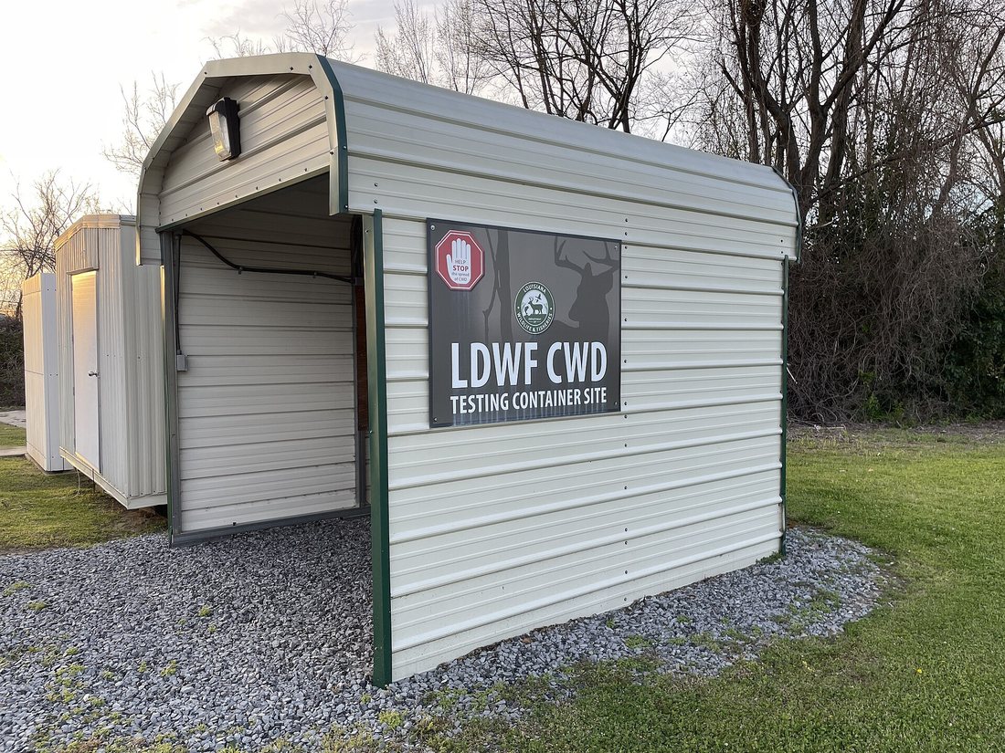 A roadside metal shed with a sign reading LDWF CWD Testing Container Site