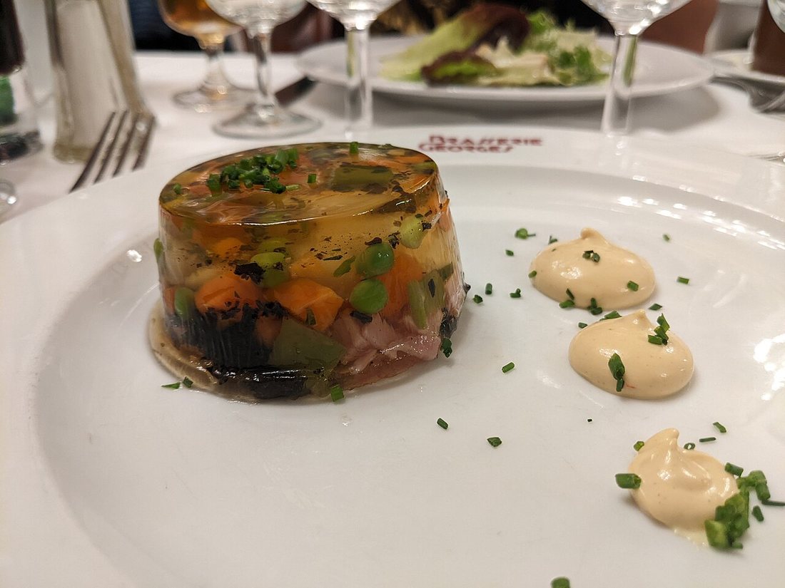 An oeuf en gelée at Brasserie Georges in Lyon: a round aspic with diced vegetables and ham around the egg, with dots of mayonnaise