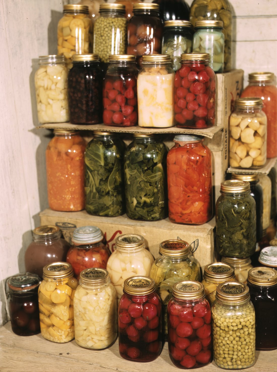 A home-canning shelf of put-up fruit and vegetables. This is not Grandma Hay's shelf — but it is the shape of what she kept