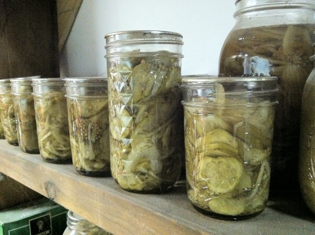 Jars of pickles on a wooden shelf. The only thing missing is a date written on every lid