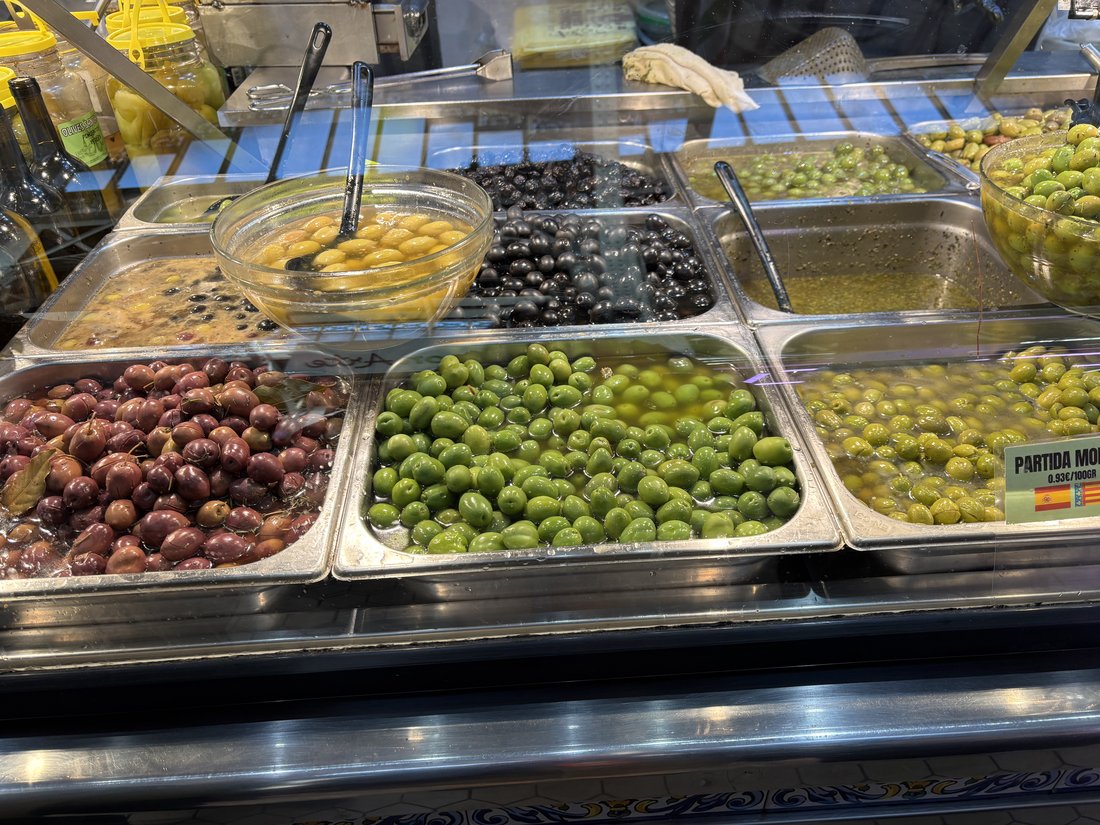 A market counter with many cures of olive side by side. Every one of them started as a fruit nobody could eat