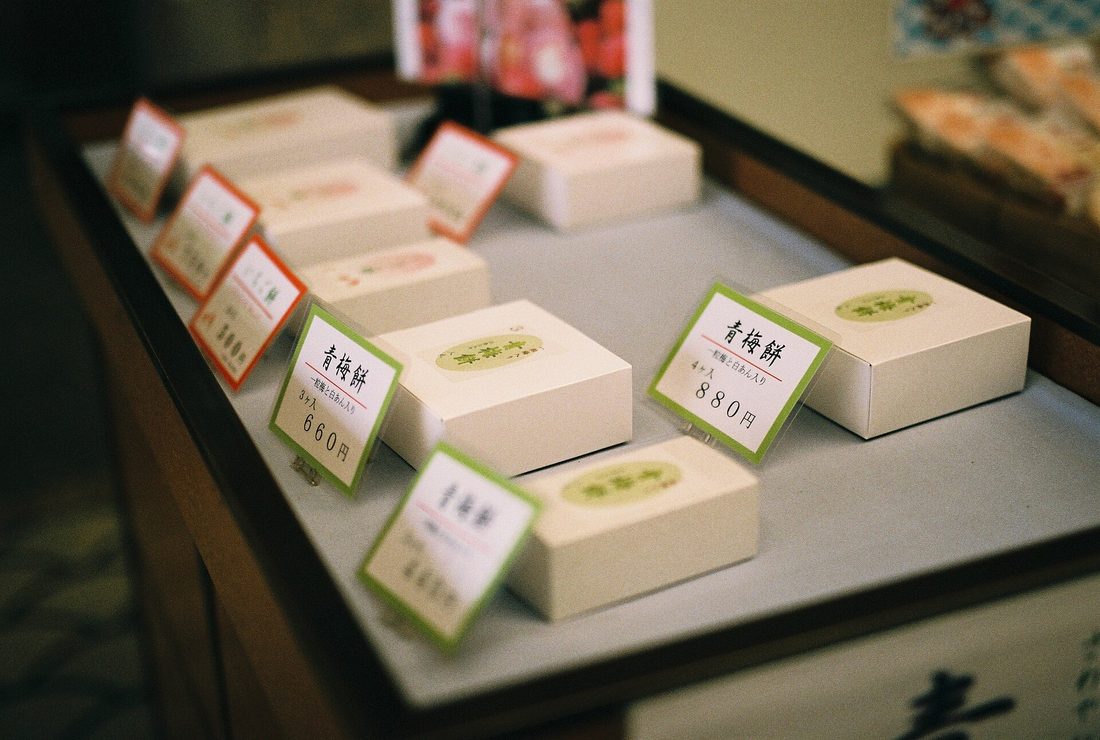 A wooden mallet mid-strike in a mortar of glistening pounded mochi, the sticky rice smeared into a single elastic mass