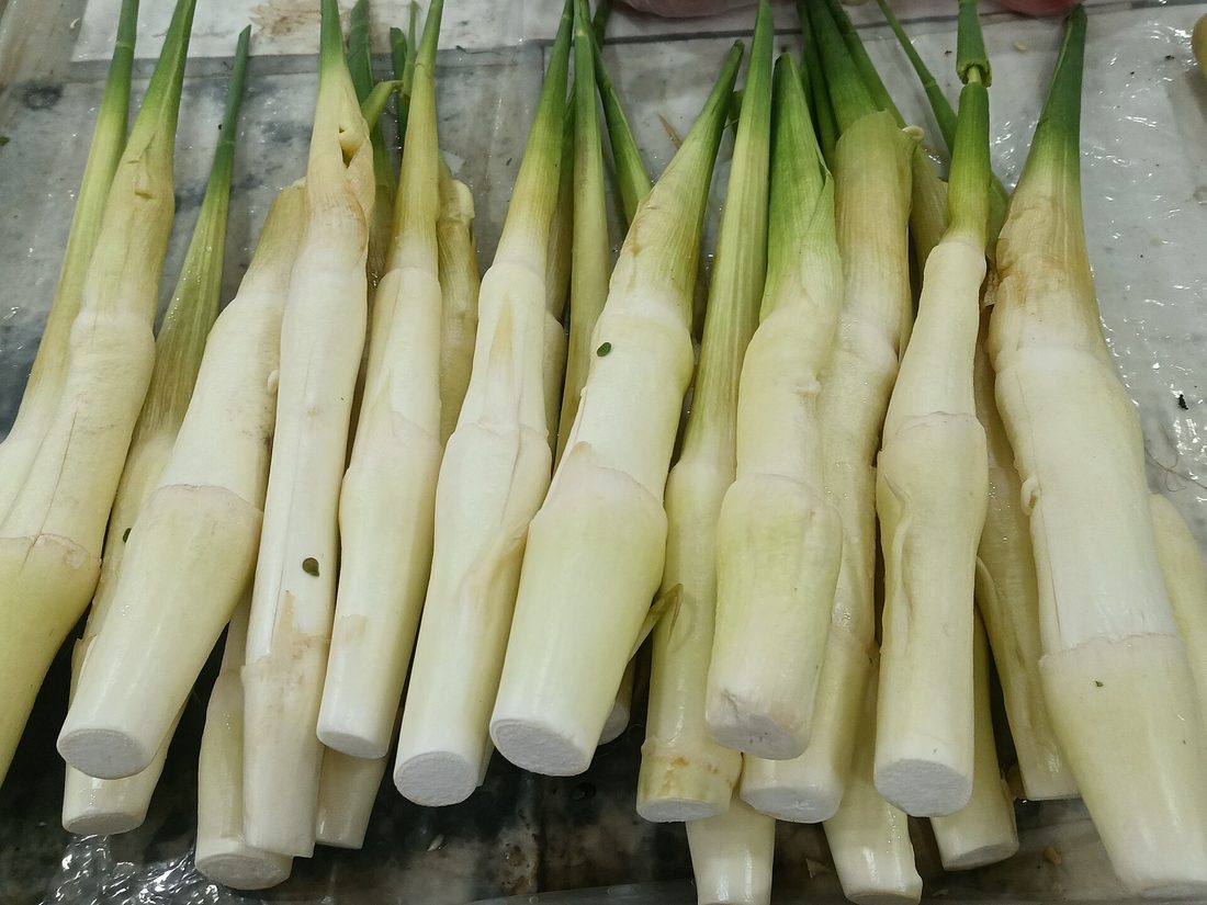 A plate of stir-fried jiaobai — pale, peeled, crescent-cut water-bamboo shoots — a Chinese vegetable made from fungus-infected Manchurian wild rice