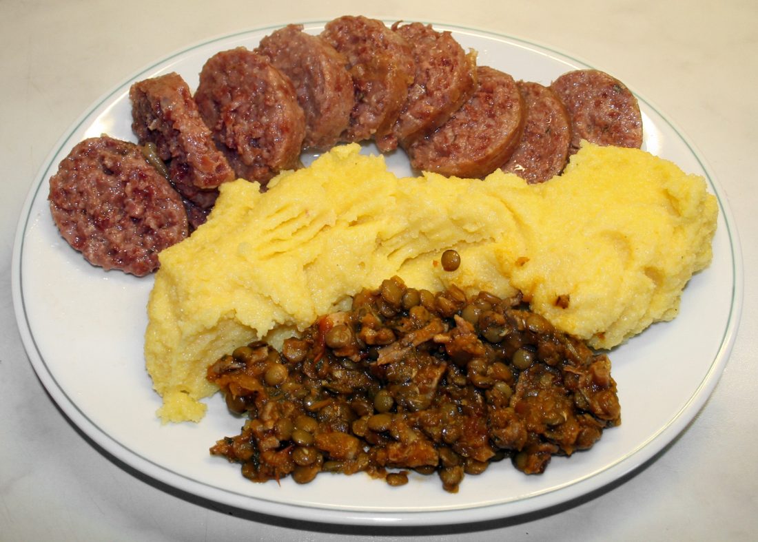 Cotechino with lentils — the thick cooked pork sausage of Modena, a New Year's dish tied to the 1511 siege of Mirandola.