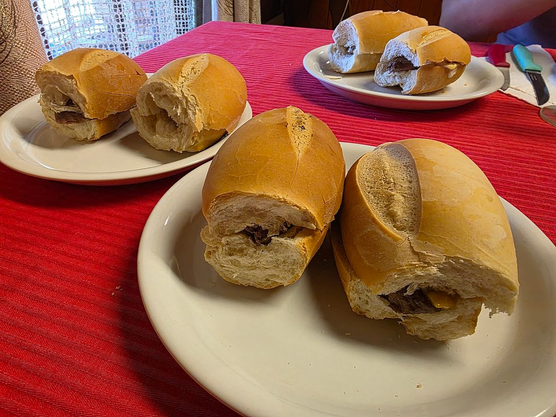 Choripán — the Argentine grilling chorizo split into a crusty roll: a fresh sausage, not the Spanish dry kind, its smoke coming from the coals.