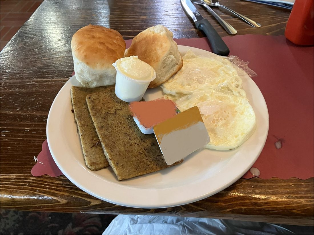 Scrapple, sliced and pan-fried — the Pennsylvania Dutch mush-loaf bound with cornmeal. The grain tells the city.