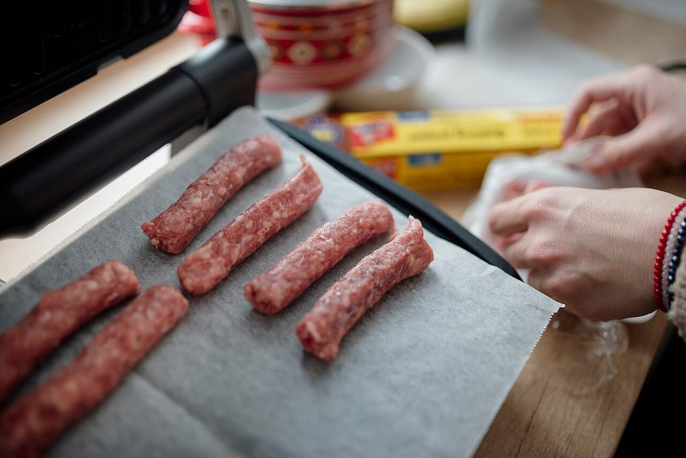 A coil of coarse-ground fresh kielbasa in natural hog casing, twisted into six-inch links, the fat still in distinct white flecks rather than smeared into a paste
