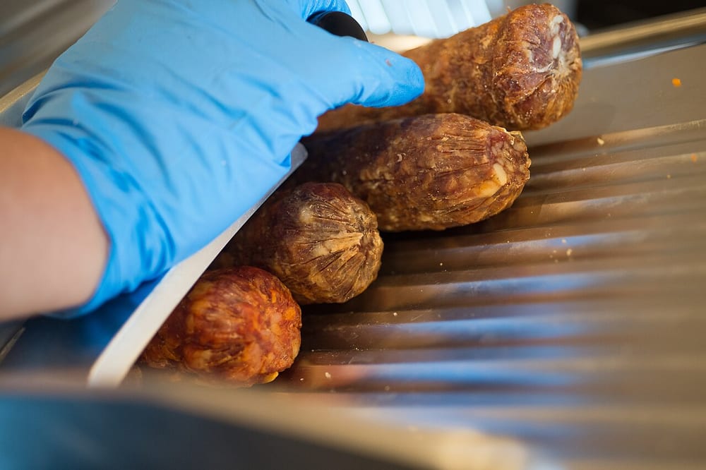 Coarse-ground smoked sausages sliced across, the distinct grains of meat and fat held in a tight matrix