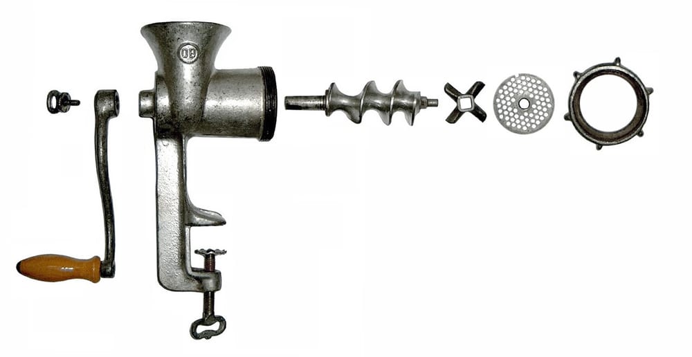 A grinder head disassembled — the auger, the four-wing knife, and a 1/4-inch plate laid out on a towel