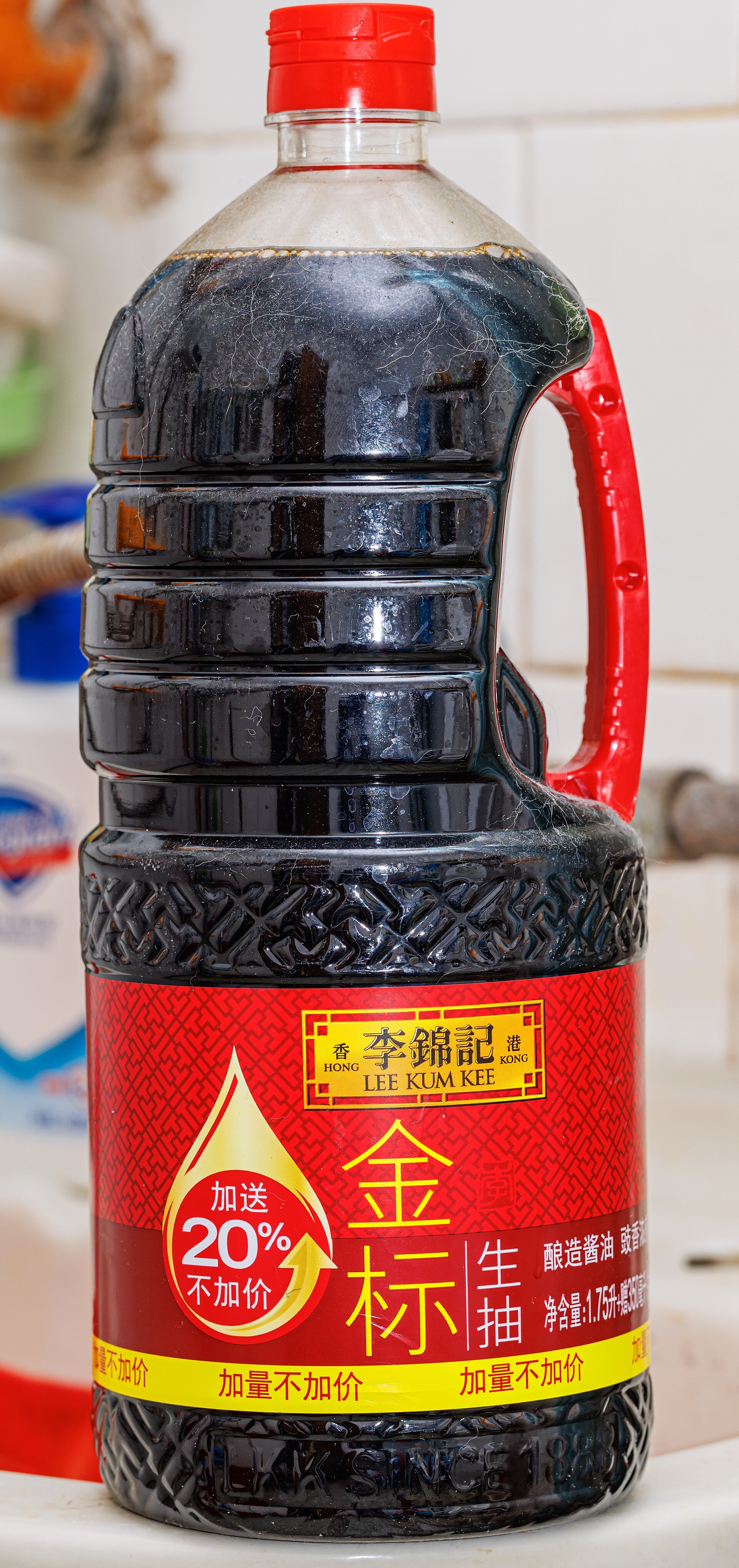 A large jug of light soy sauce, the label reading 金標生抽 — gold label fresh-draw