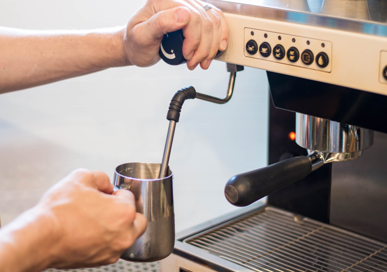 The steam wand plunged into a pitcher of egg, mid-cook