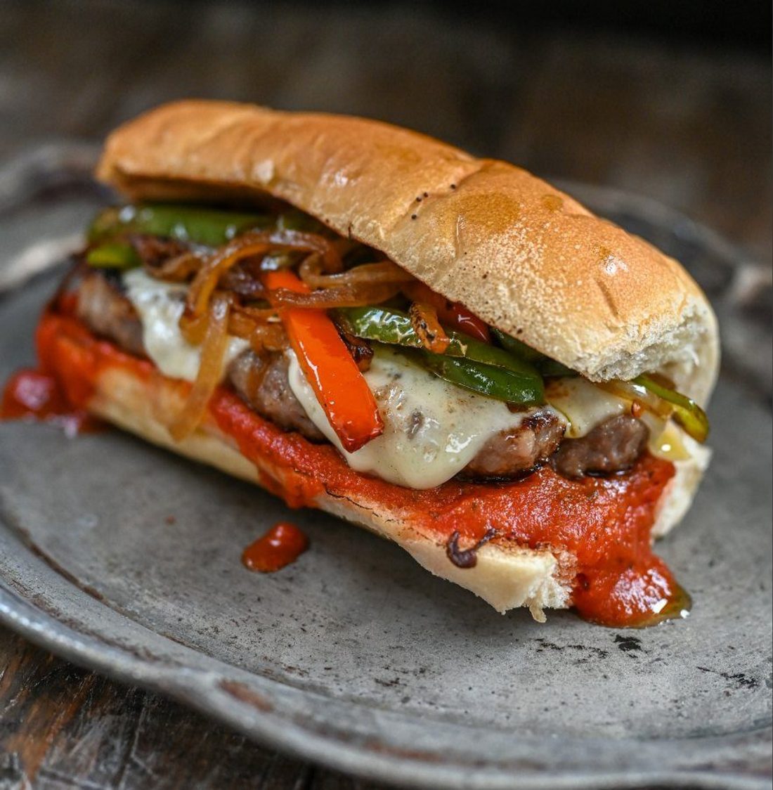 A traditional cudighi sandwich — spiced Italian sausage patty on a bun with sauce and cheese