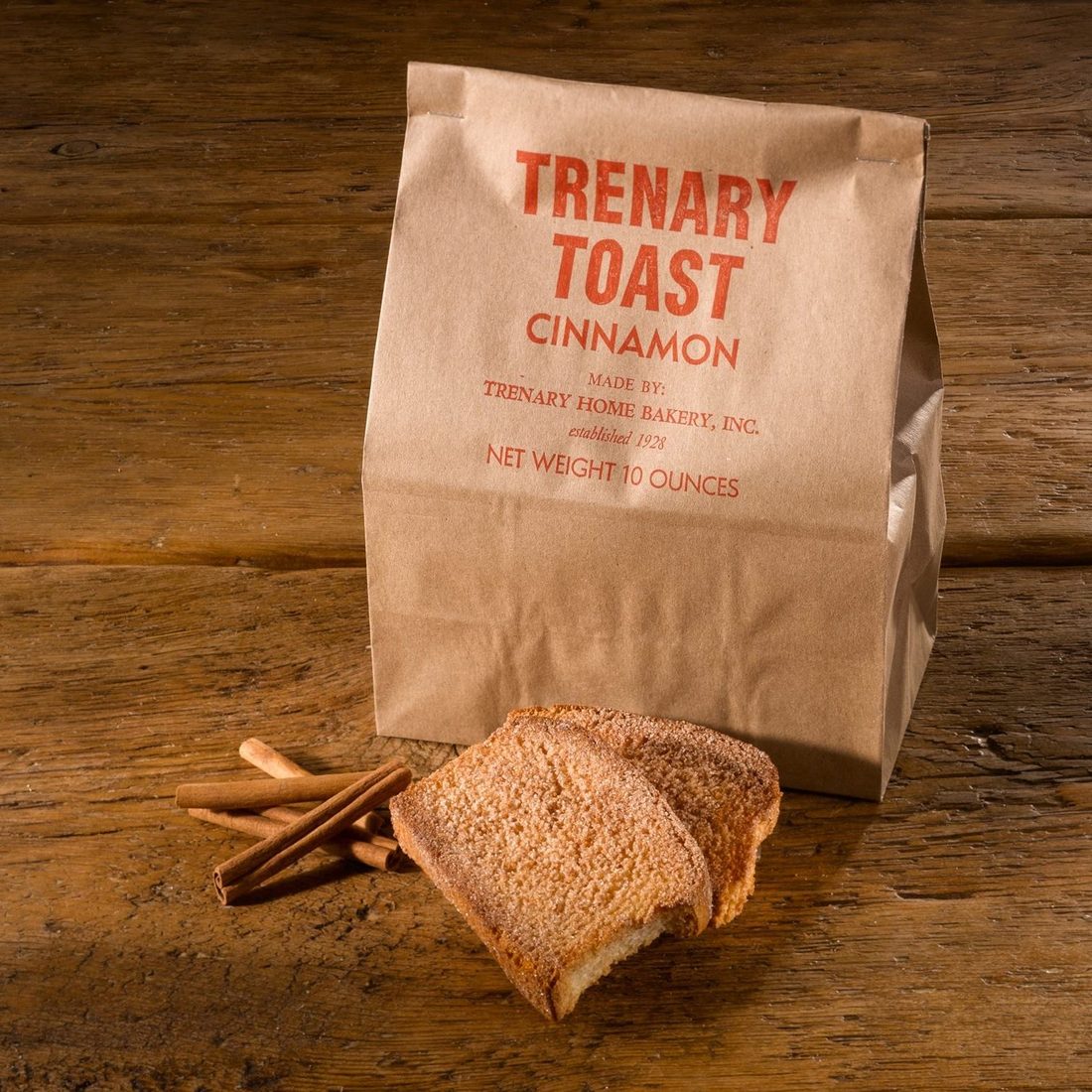 A brown paper bag of Trenary Toast with slices of the hard cinnamon-sugar rusk beside it