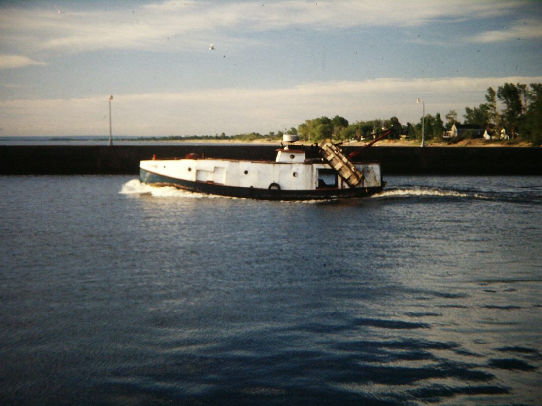 A Great Lakes commercial fish tug at dock, enclosed steel hull with the cabin run forward