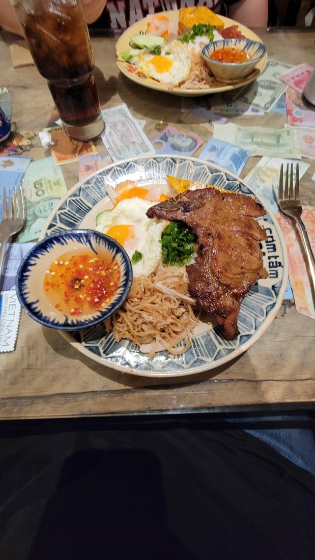 The plate: broken rice, a grilled pork chop, a fried egg, cucumber and tomato, and a bowl of nước chấm on the side