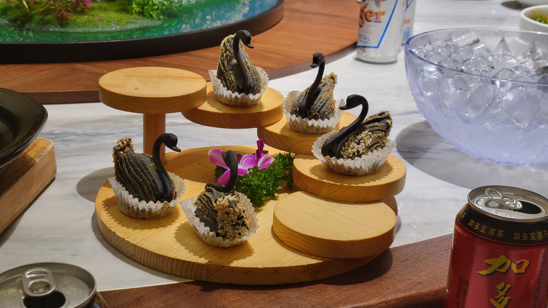 Hand-formed durian pastries on a tiered stand, dark and spiked, in paper cases