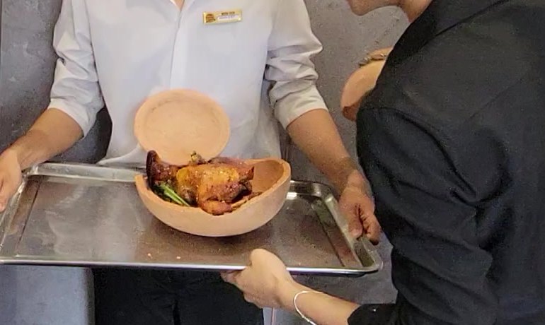 The bird in the bottom half of its own pot, on the lemongrass it cooked on, with the cap resting alongside